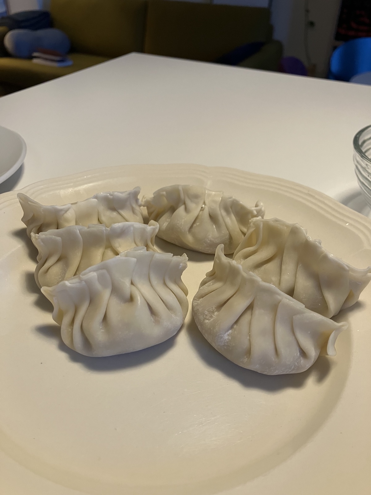 six uncooked dumplings on a plate